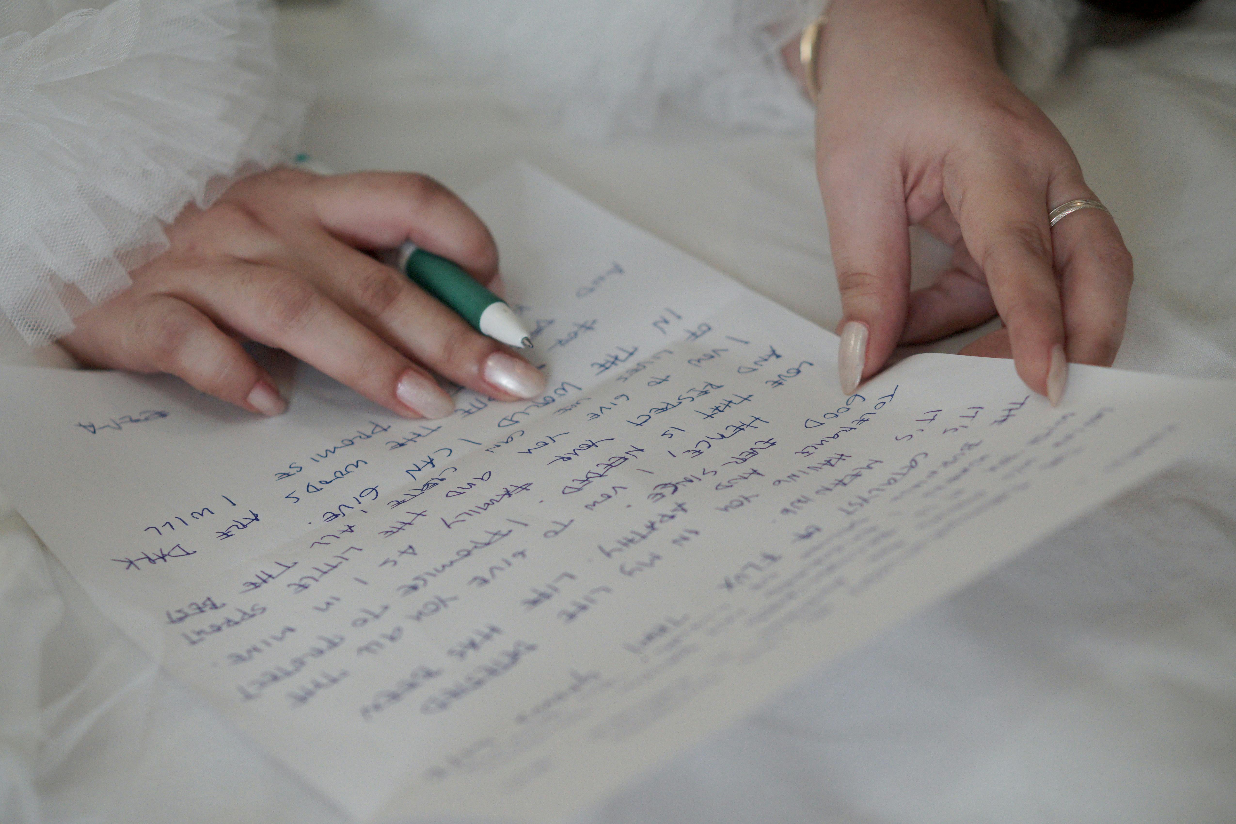 A woman's hands holding a pen while writing a letter | Source: Pexels