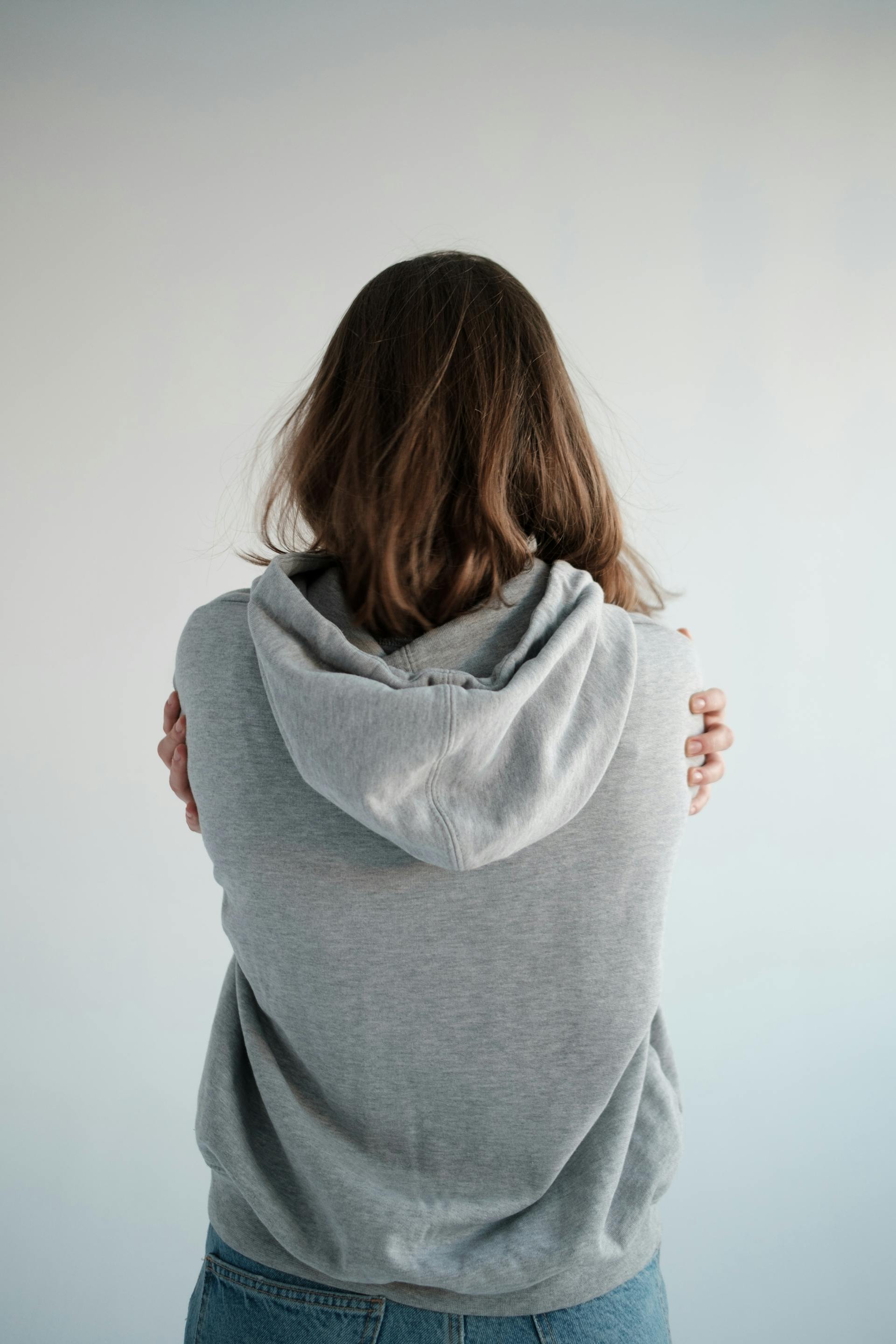 Young woman in a hoodie standing with her back facing the camera | Source: Pexels