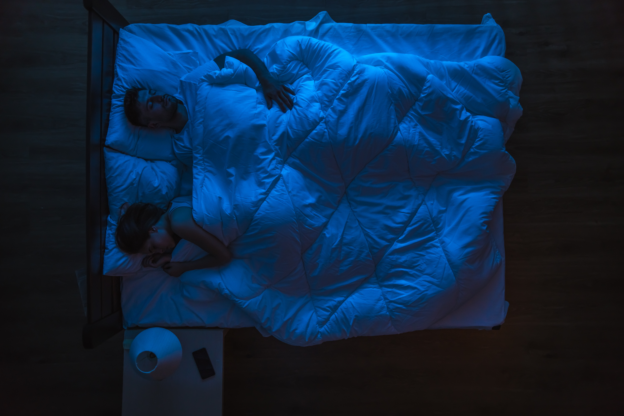 The couple sleeping on a bed. Evening night time. | Source: Shutterstock