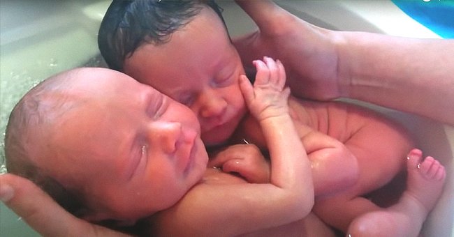 Bebés gemelos abrazados en un video compartido por una enfermera bañándolos. | Foto: YouTube/massagebebe