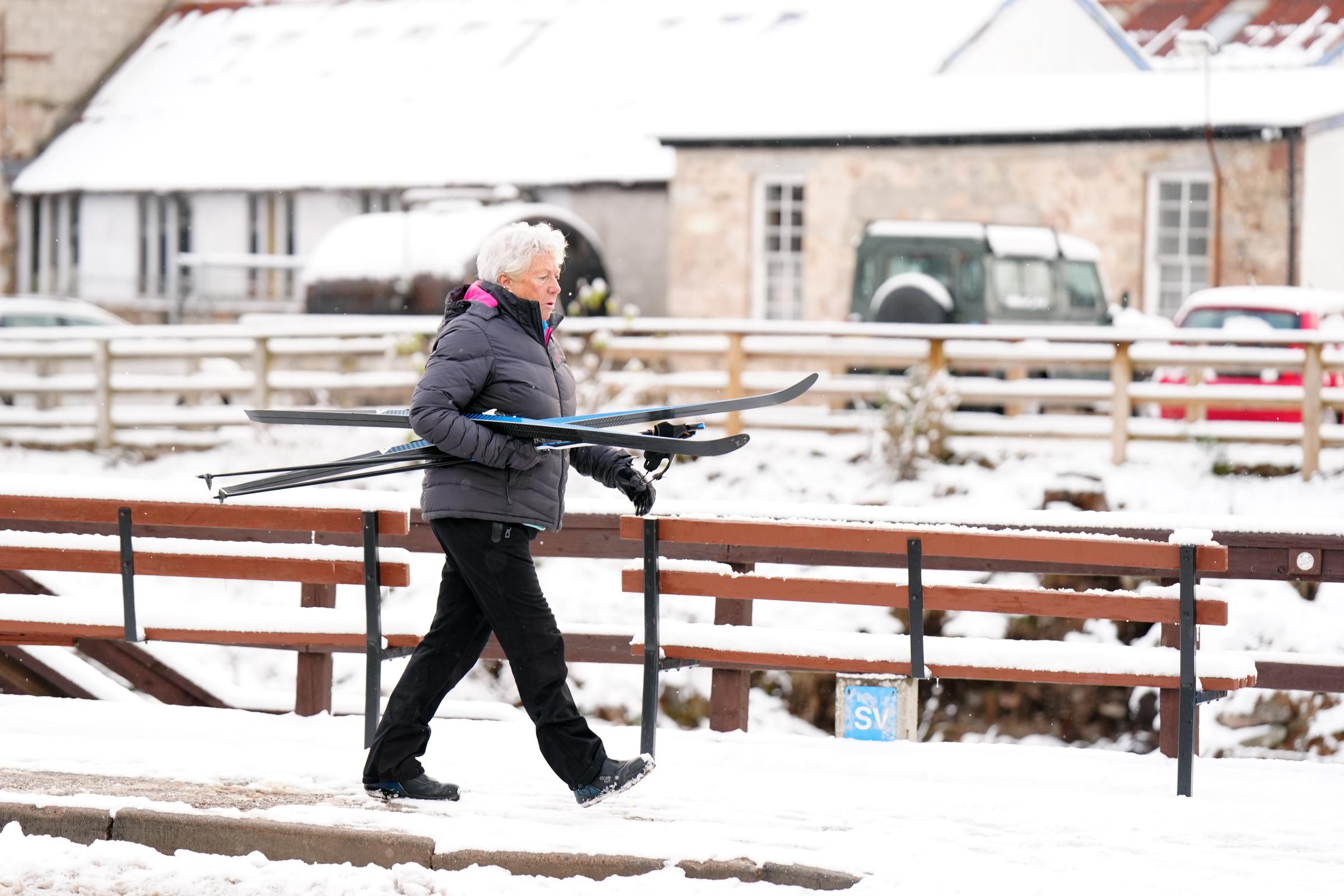 A person walking through snow with a pair of skis in Carrbridge in the Scottish Highlands on November 19, 2025. | Source: Getty Images