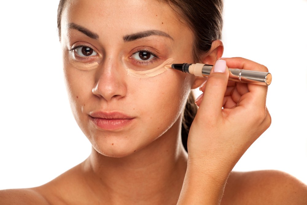 Mujer aplicándose corrector debajo de los ojos. | Foto: Shutterstock