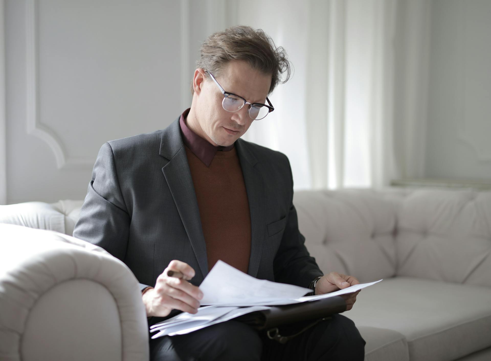 A man going through important documents while sitting on a couch | Source: Pexels