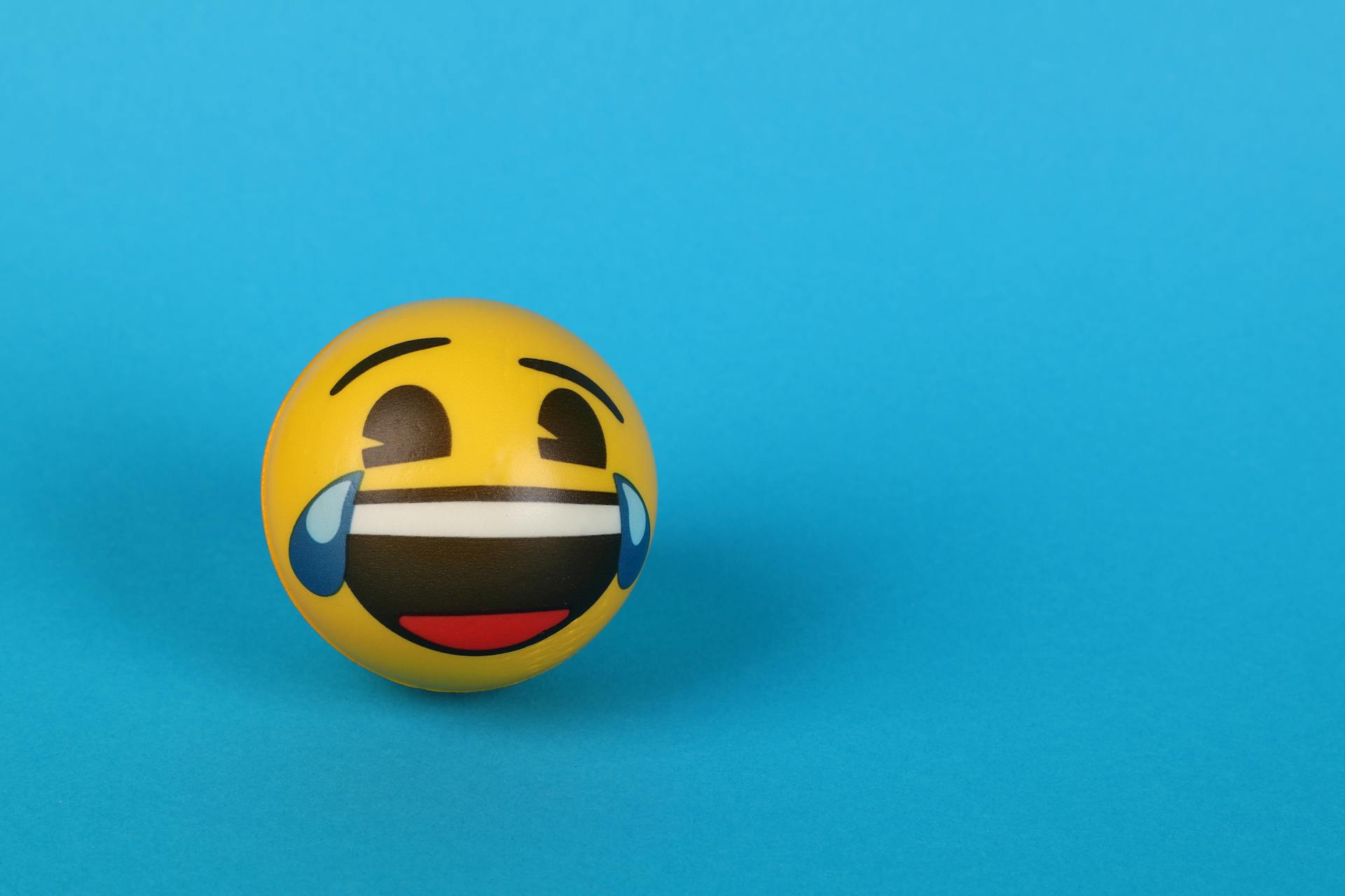 A laughing emoji with tears over a blue surface | Source: Pexels