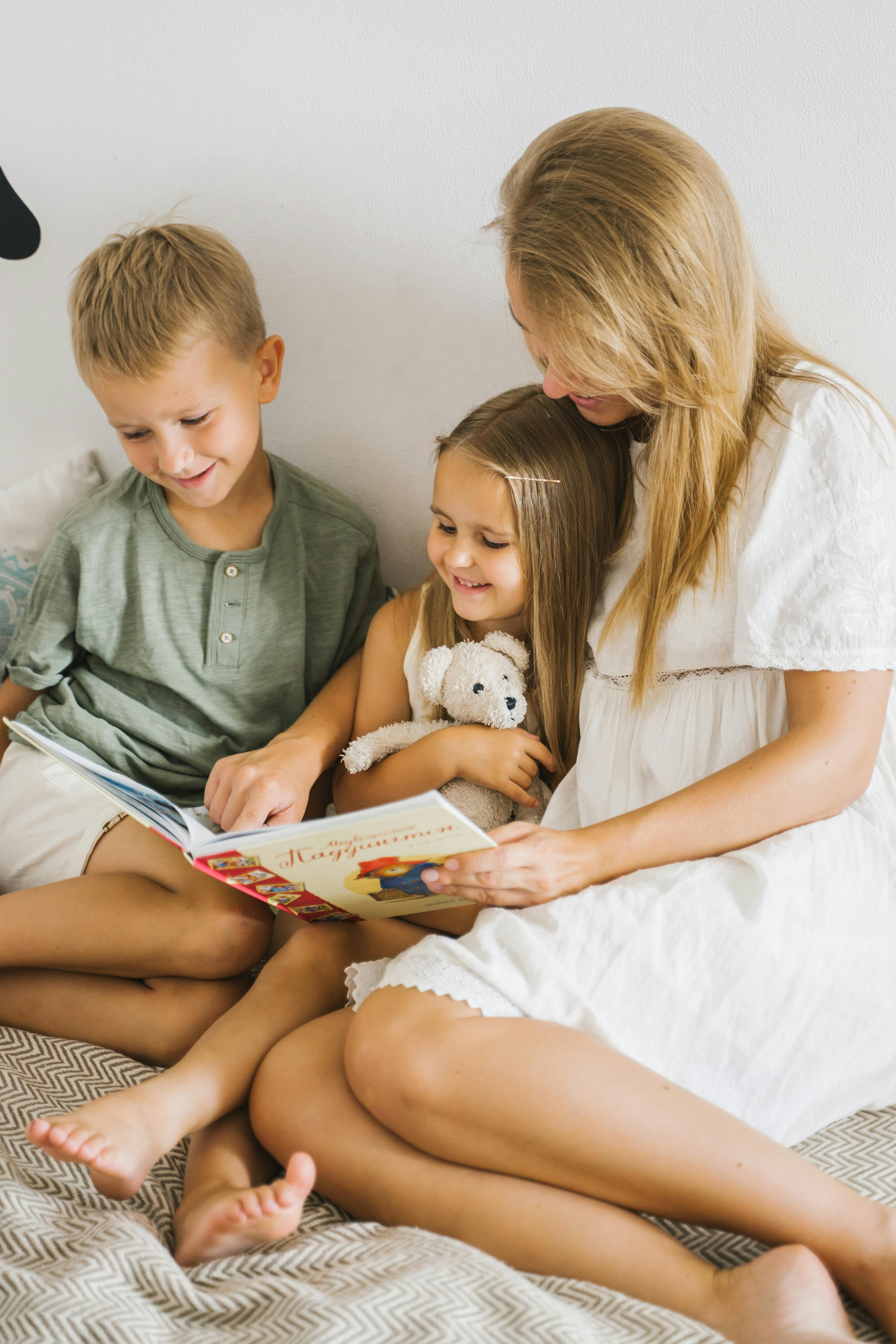 A woman reading a book to two children | Source: Pexels