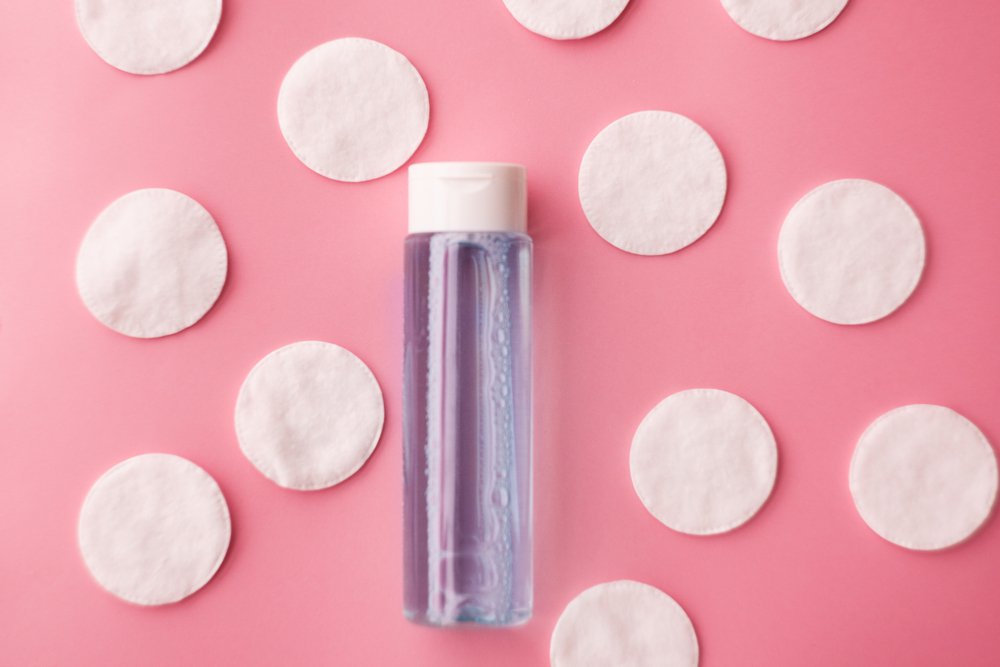 Botella de tónico facial rodeada de esponjas faciales de algodón. | Foto: Shutterstock