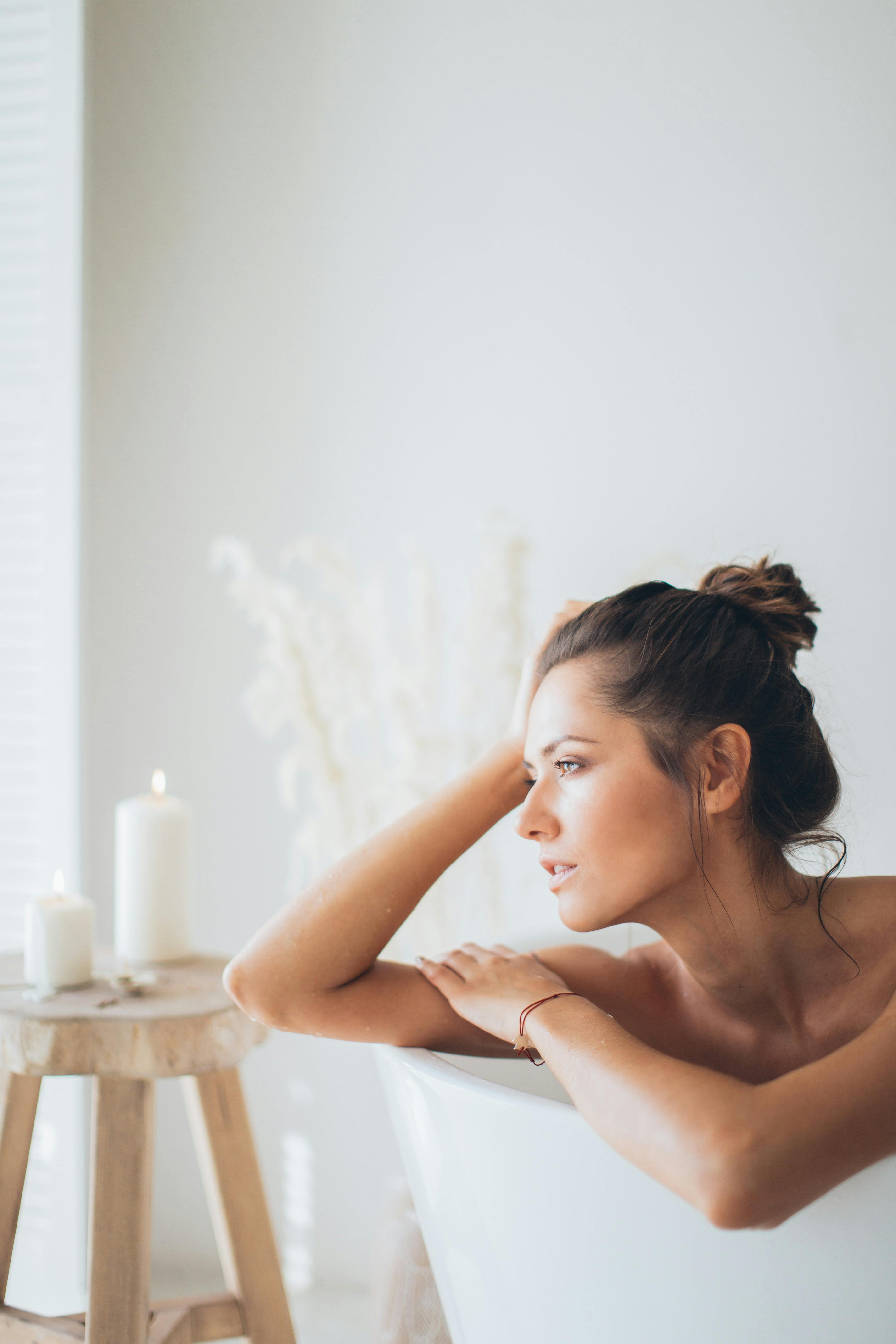 A woman relaxes in a bathtub beside lit candles. | Source: Pexels