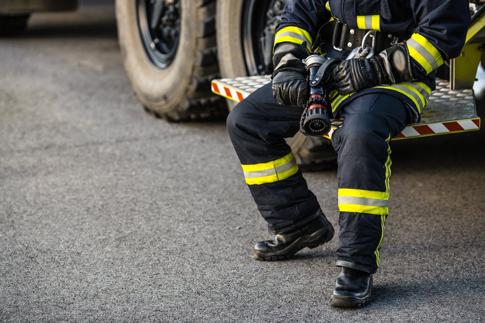 Feuerwehrmann sitzt mit einer Taschenlampe in der Hand. | Quelle: Shutterstock
