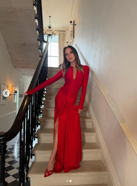 Victoria Beckham poses on a staircase in a floor-length red gown with a thigh-high slit and matching heels in a Valentine's Day post dated February 14, 2026. | Source: Instagram/victoriabeckham