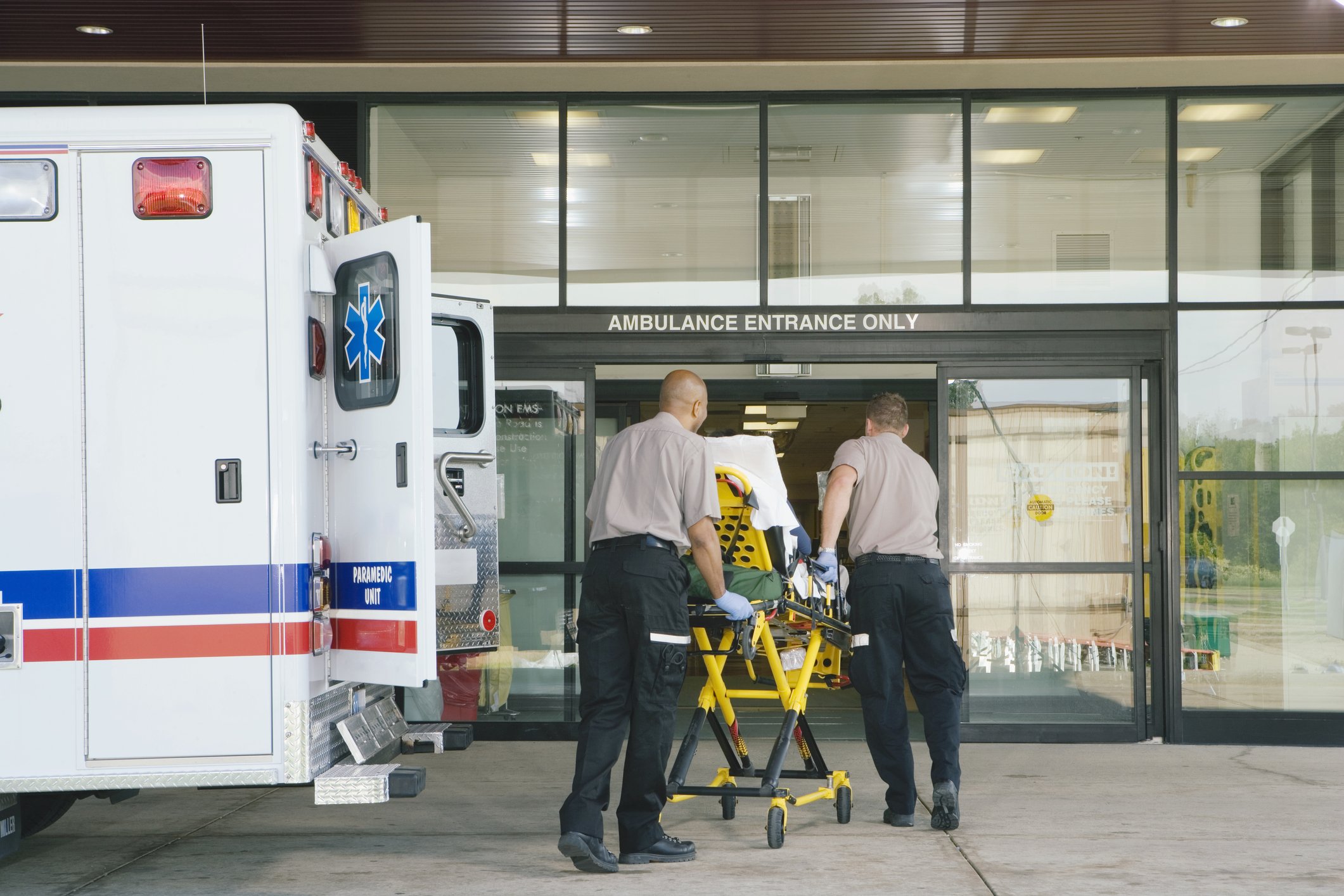 Paramedics taking patient on stretcher from ambulance to hospital. | Photo: Getty Images