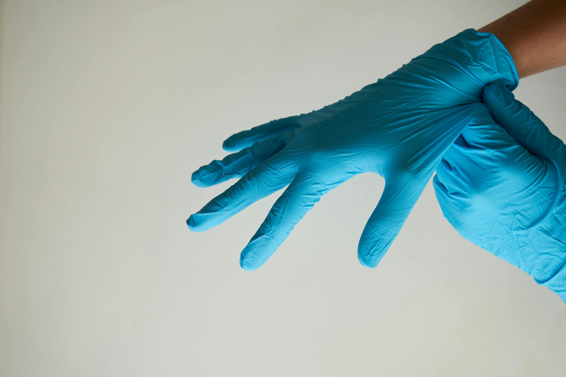 A woman putting on blue latex gloves | Source: Pexels