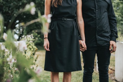 A couple holding hands at a grave site. | Source: Shutterstock.