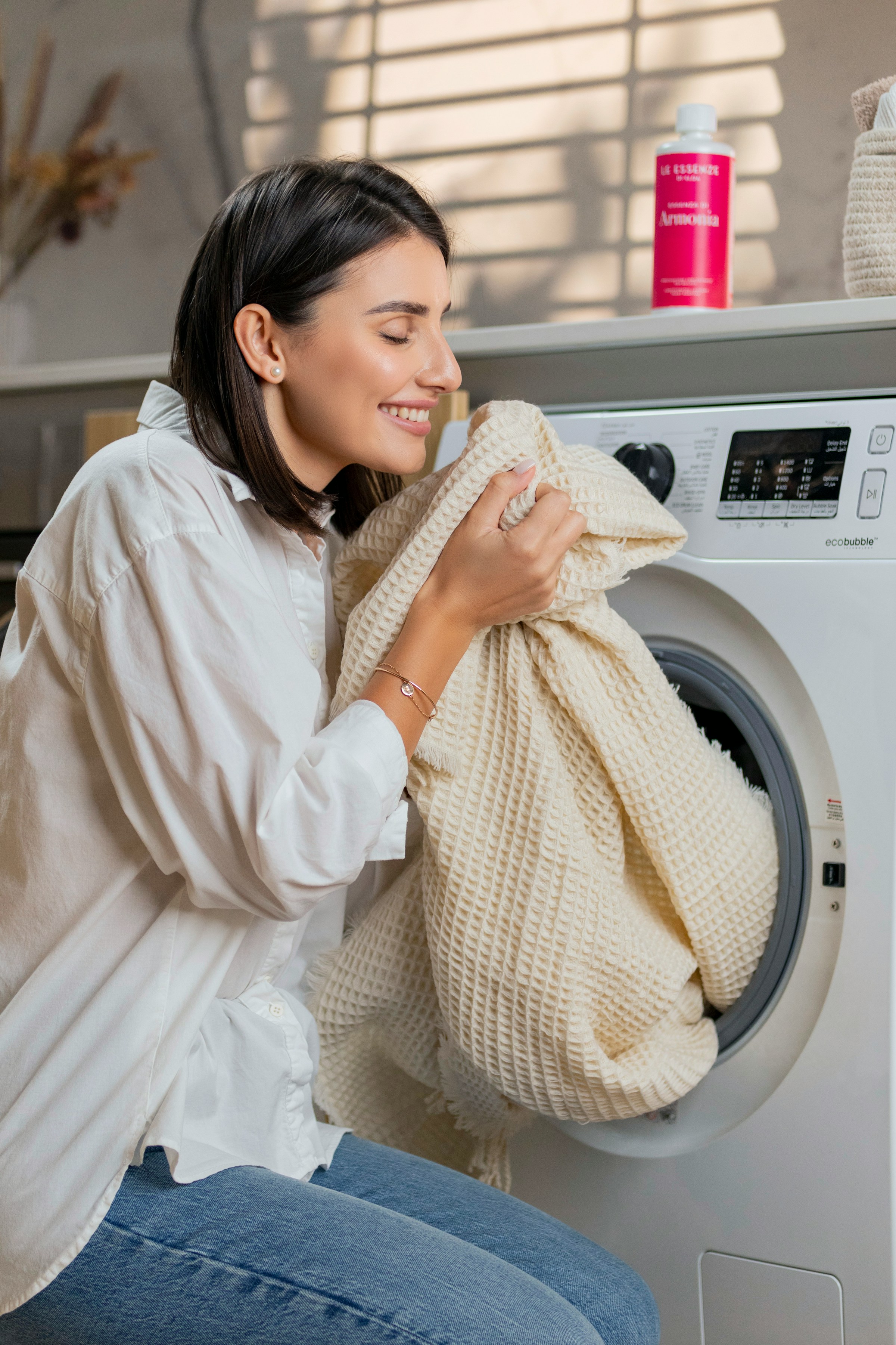 A smiling woman smelling washed laundry | Source: Unsplash