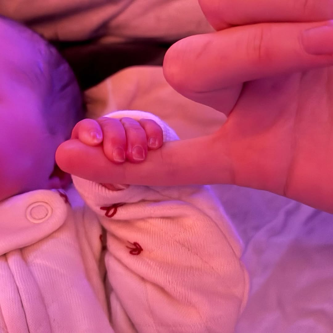 Scottie Rose Hewitt Davidson holds onto a finger in a close-up moment shortly after birth, as posted on December 18, 2025 | Source: Instagram/elsie