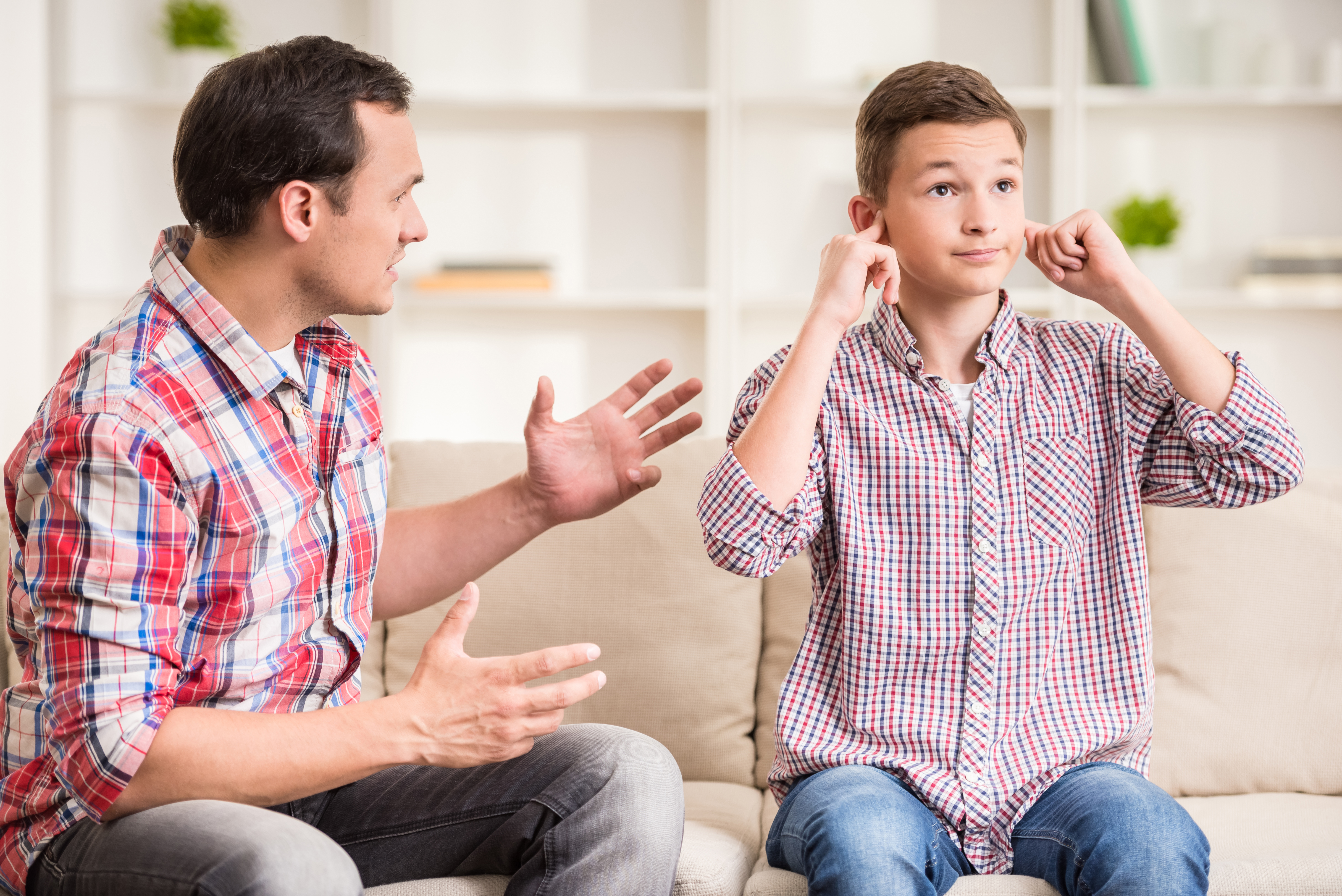 Son closing his ears to his father's lecture. | Source: Shutterstock
