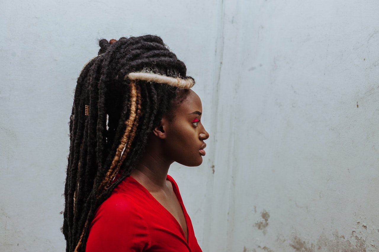Photo of a young black woman with dreads looking away | Photo: Pexels