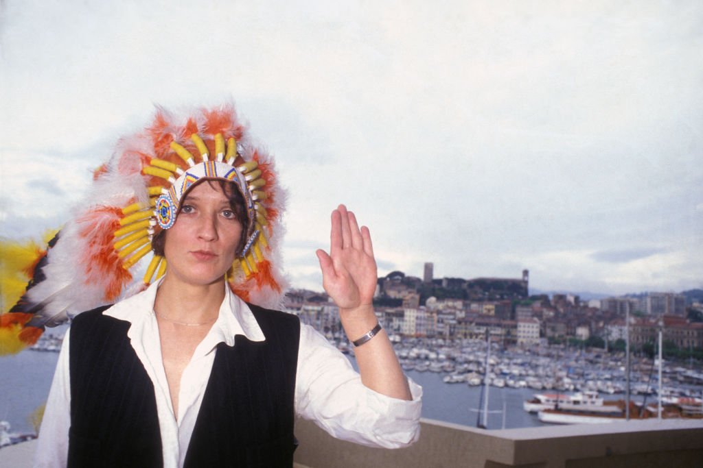 Portrait of Corine Marienneau, singer and bassist of the French rock band Telephone, wearing an Indian headdress with feathers in front of a fishing port, around 1980. |  Photo: Getty Images