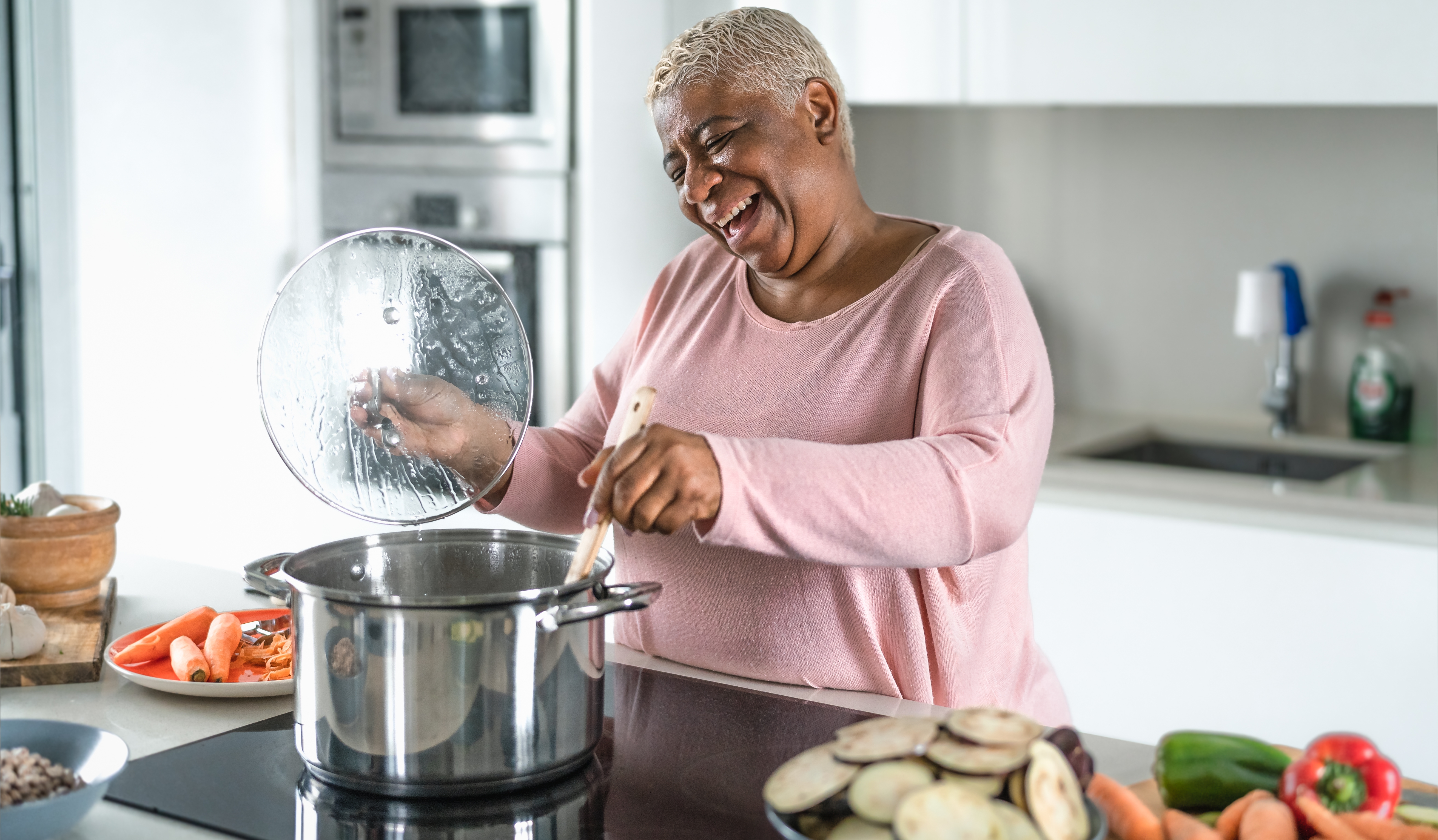 Mujer mayor sonriendo mientras cocina. | Foto: Shutterstock