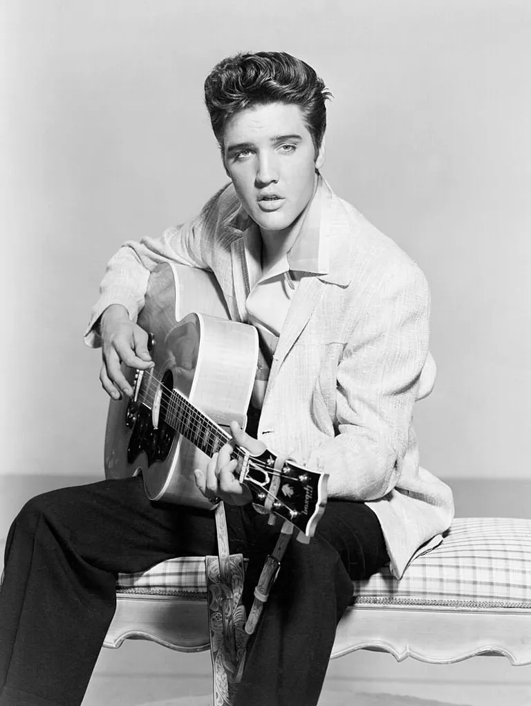 Elvis Presley strums his acoustic guitar in a portrait in 1956. | Source: Getty Images