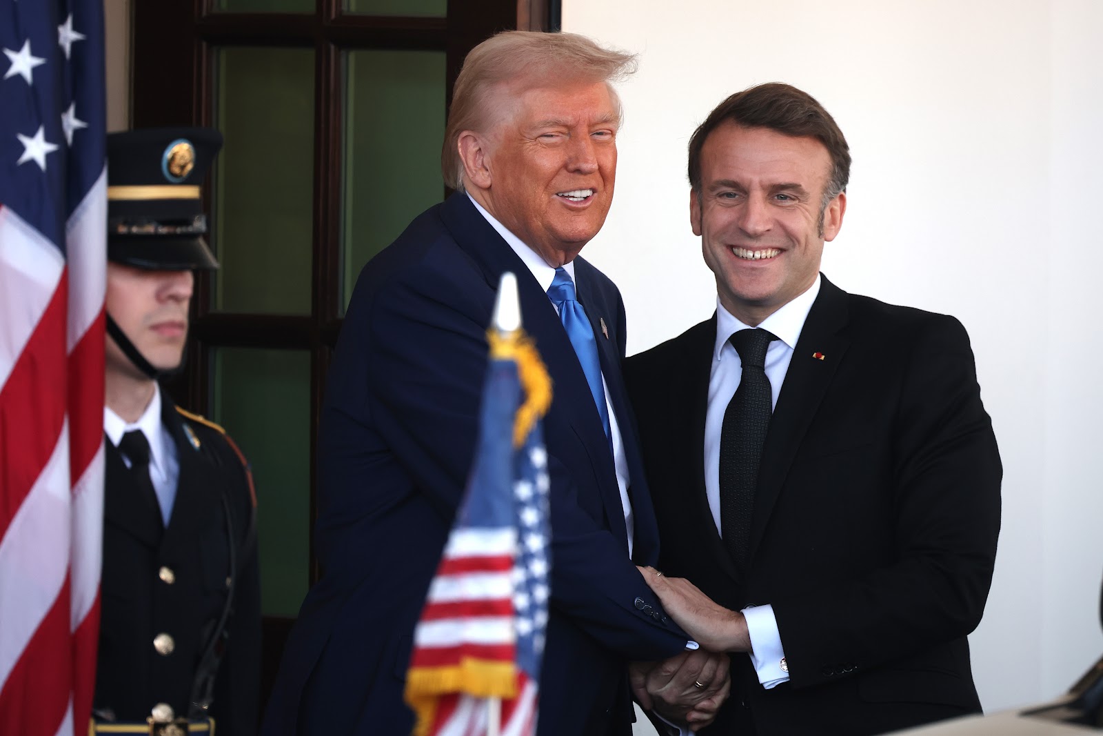 Donald Trump and Emmanuel Macron smiling and shaking hands. | Source: Getty Images