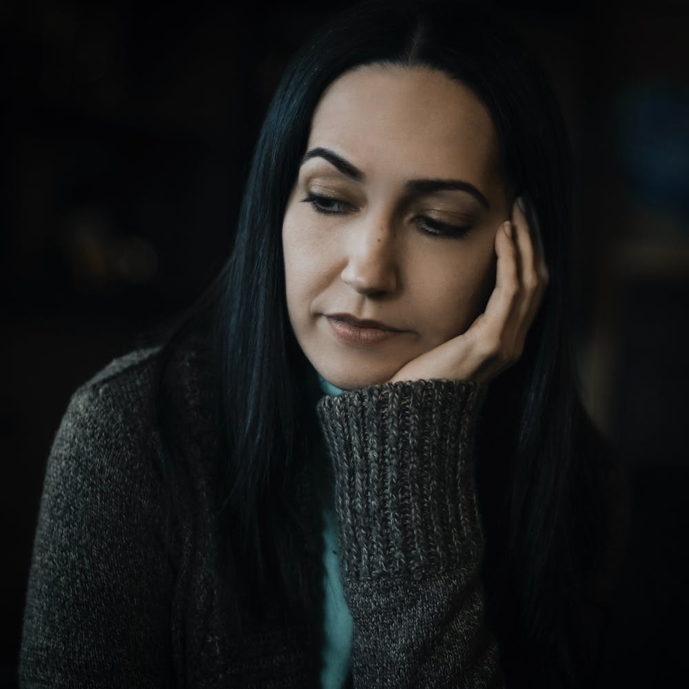 Woman wearing gray sweater, deep in thought. | Photo: Pexels