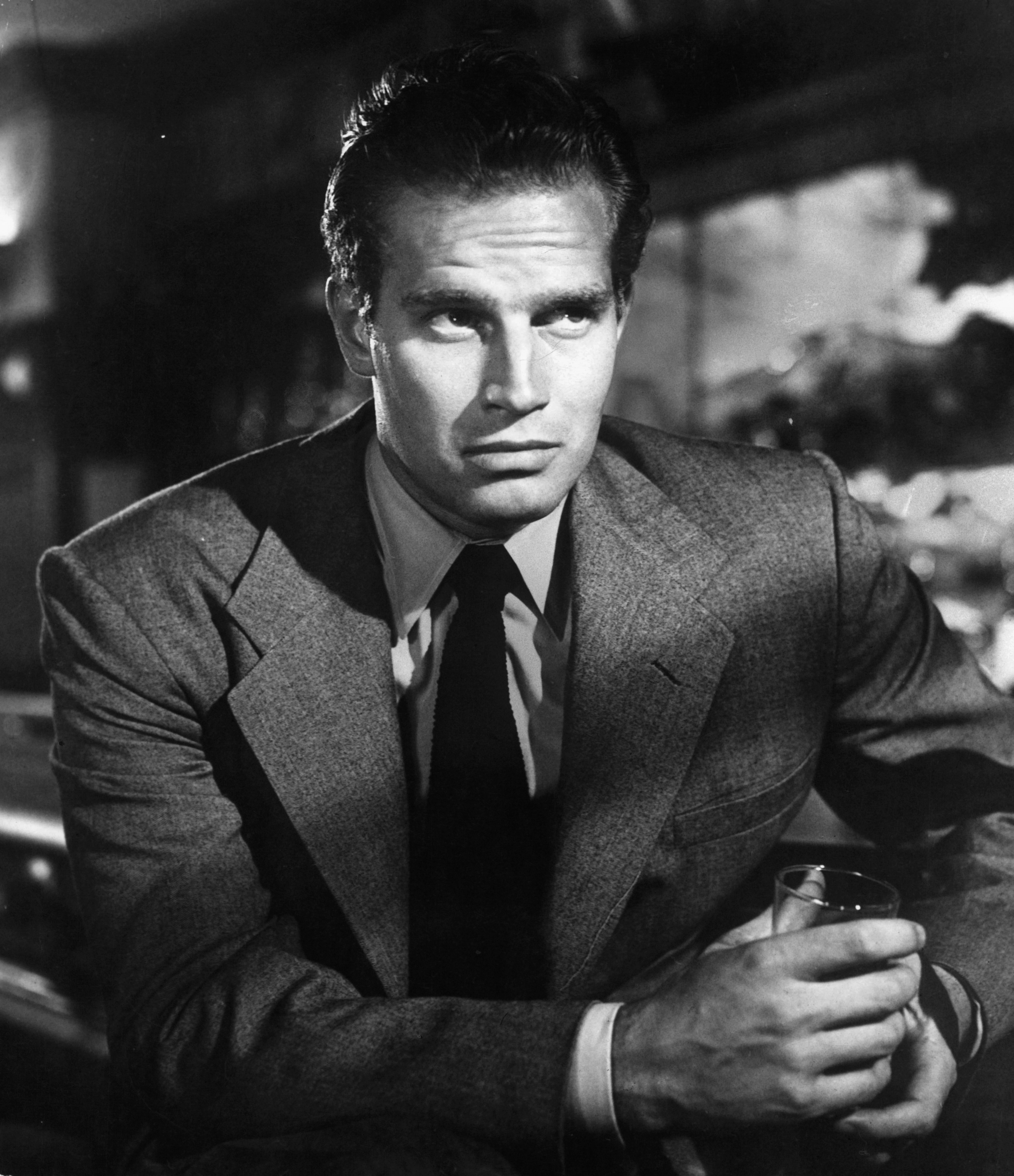 A photo of Charlton Heston holding a drink in a scene from the film 'Dark City', 1950 | Photo: Getty Images
