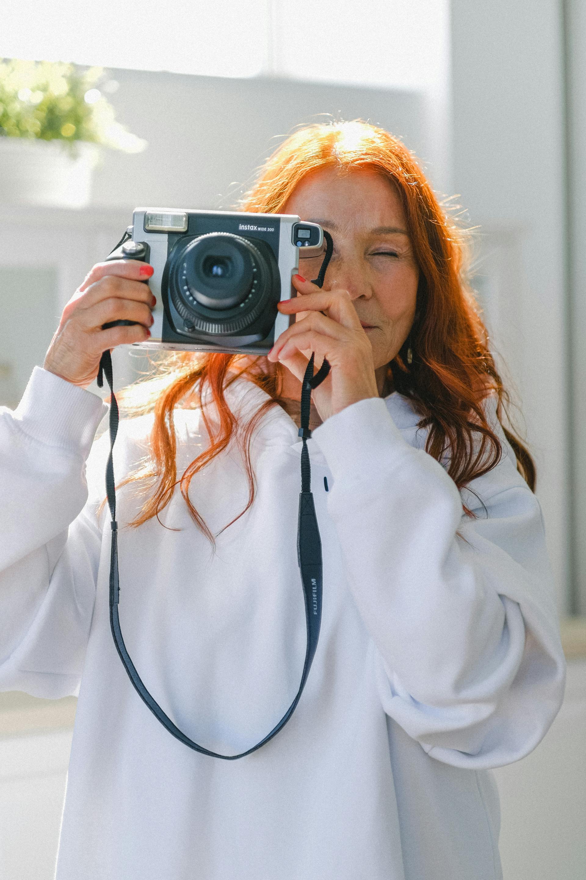 A senior red-haired woman with vintage camera | Source: Pexels