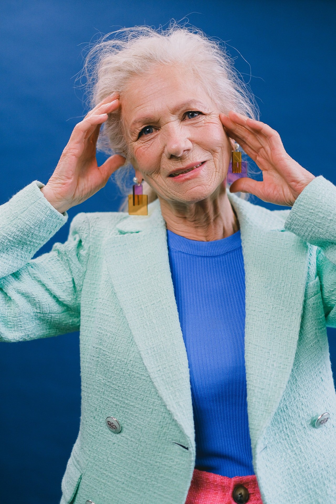 Una mujer mayor sonriente con sus manos sobre su cabeza. | Foto: Pexels