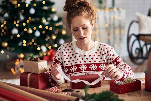 Woman tying ribbon on Christmas present | Photo: Getty Images