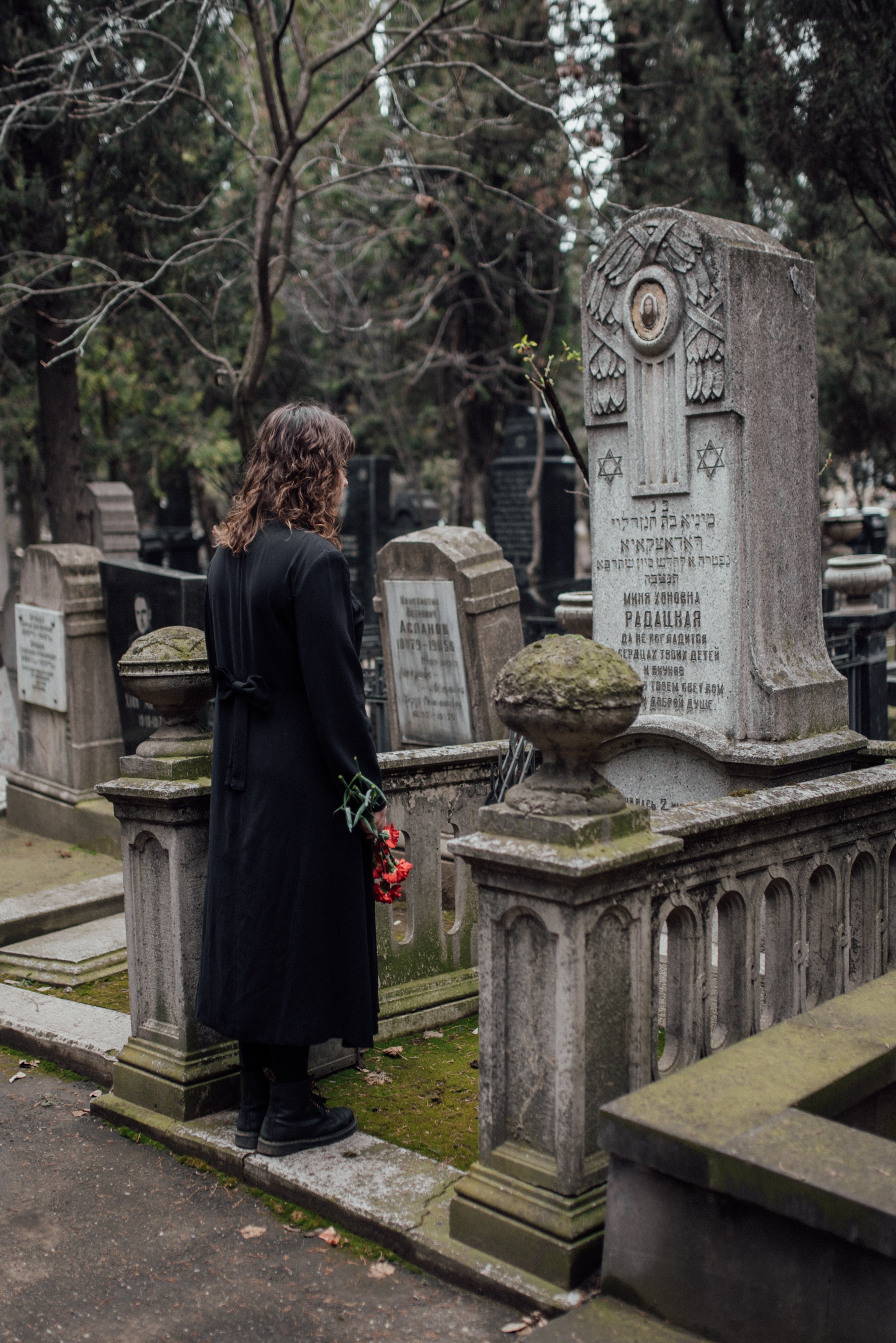Una mujer parada frente a una tumba en un cementerio. | Foto: Pexels