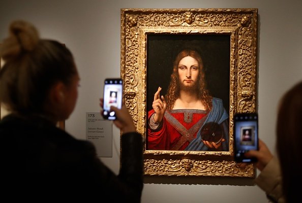 People take pictures with mobile phone at an oil painting by Leonardo da Vinci's "Salvator Mundi" on October 22, 2019 at the Louvre museum in Paris. | Photo: Getty Images