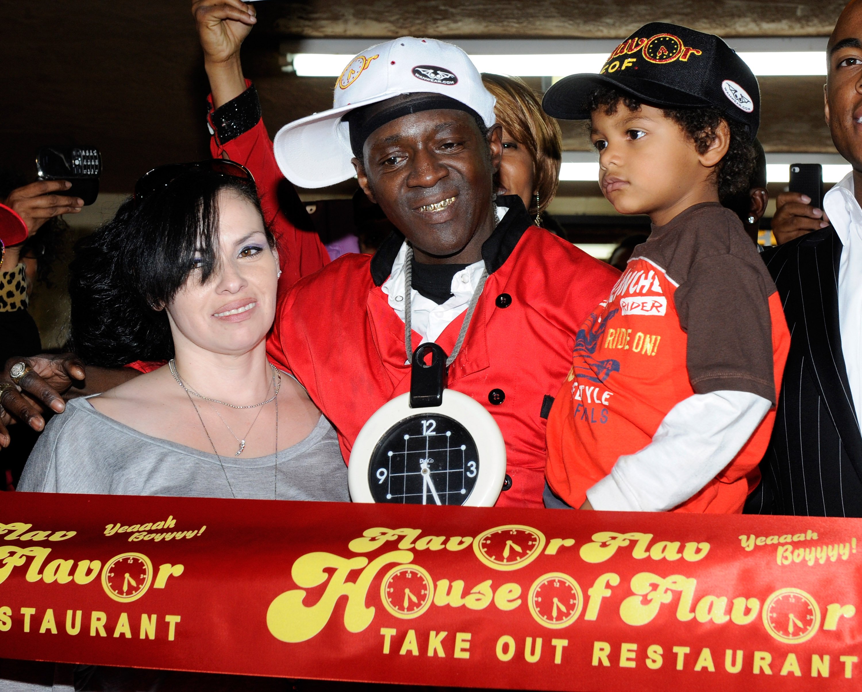 Liz Trujillo, rapper Flavor Flav and their son Karma Drayton appear during a ribbon cutting at the official grand opening of the Flavor Flav House of Flavor Take Out Restaurant on March 15, 2012 in Las Vegas, Nevada. | Source: Getty Image