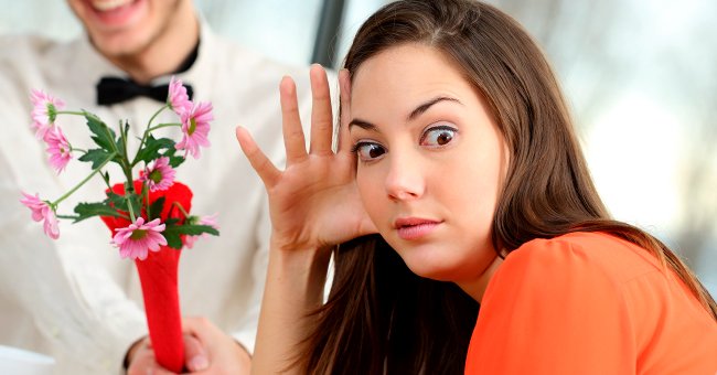 A girl hides her face while someone gives her flowers. | Photo: Shutterstock