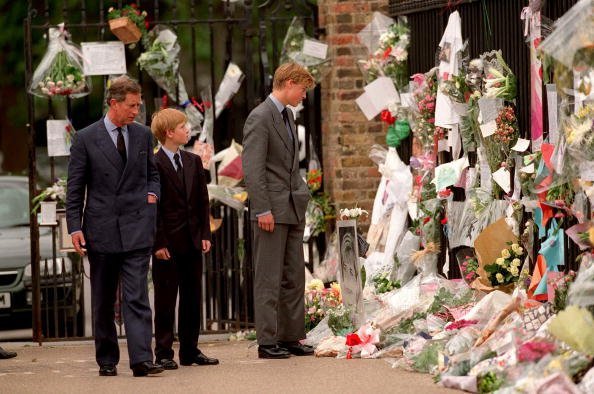 The Prince of Wales, Prince William and Prince Harry look at floral tributes to Diana, Princess of Wales outside Kensington Palace on September 5, 1997, in London, England. | Source: Getty Images.