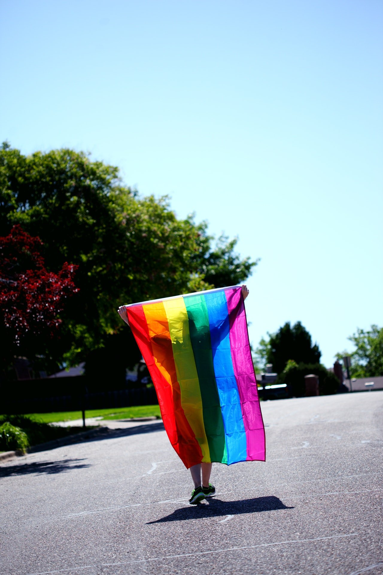 Photo of a person holding a rainbow flag | Photo: Pexels