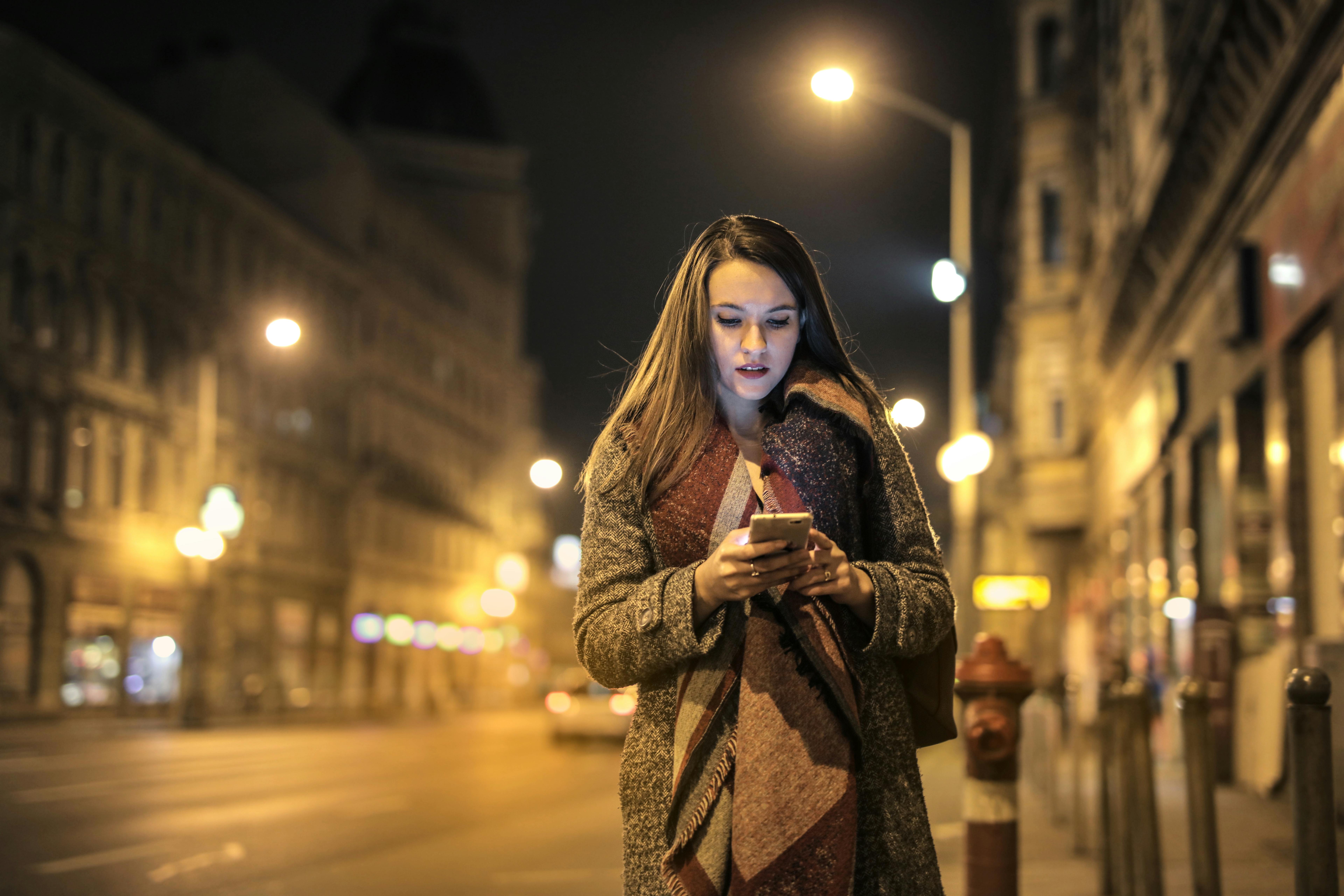 A woman making looking at her cellphone in the middle of a street | Source: Pexels