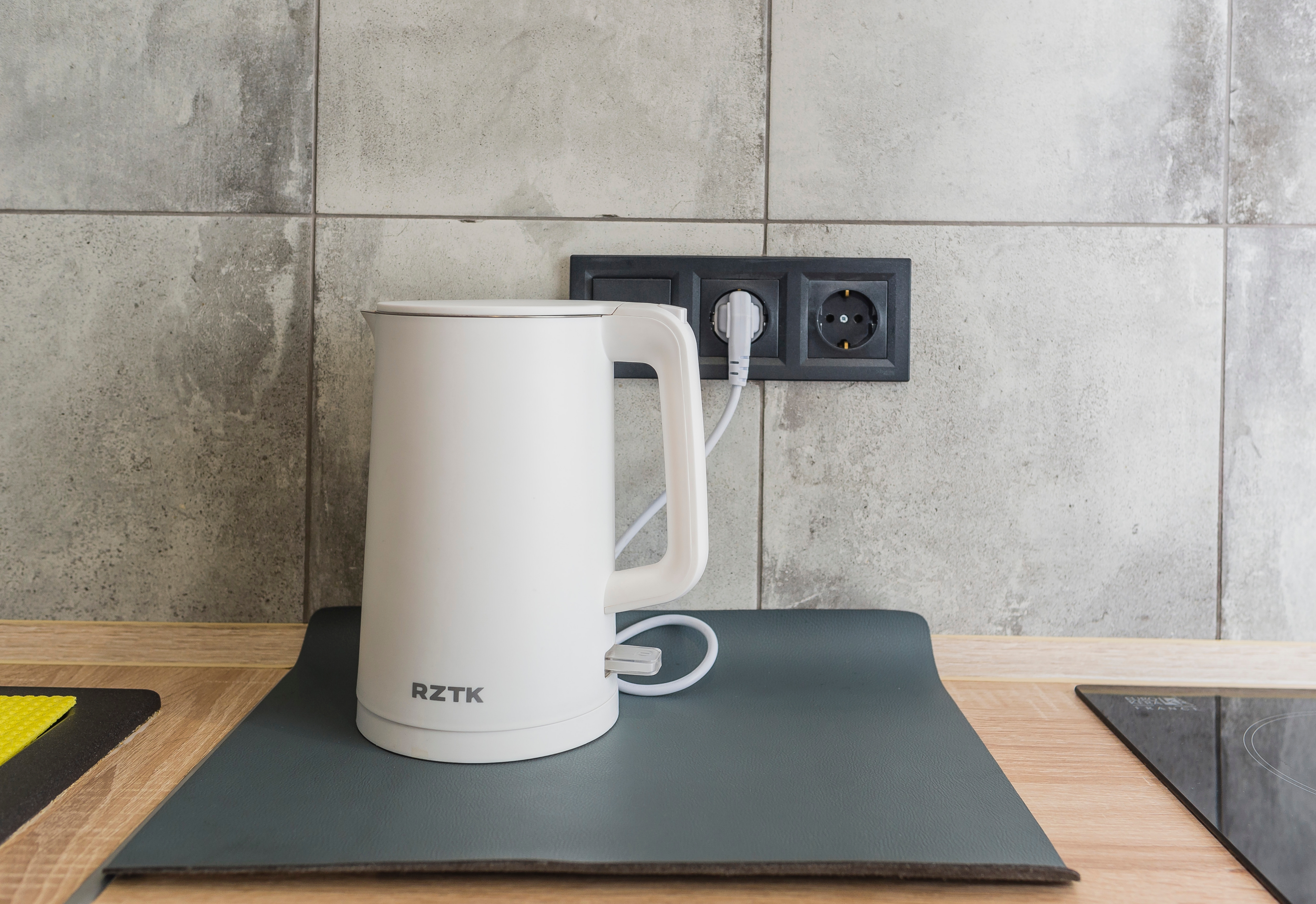 A white electric kettle standing plugged into a socket | Source: Shutterstock