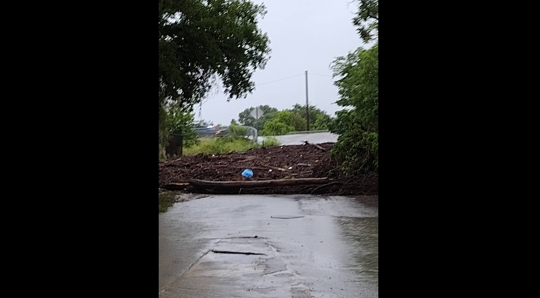 Debris deposited by flood waters blocking a paved road in Kerr County, Texas, from a Facebook post dated July 5, 2025. | Source: facebook.com/jennyandmason