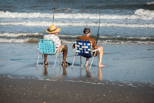 Two men fishing from the shore. | Source: Shutterstock.