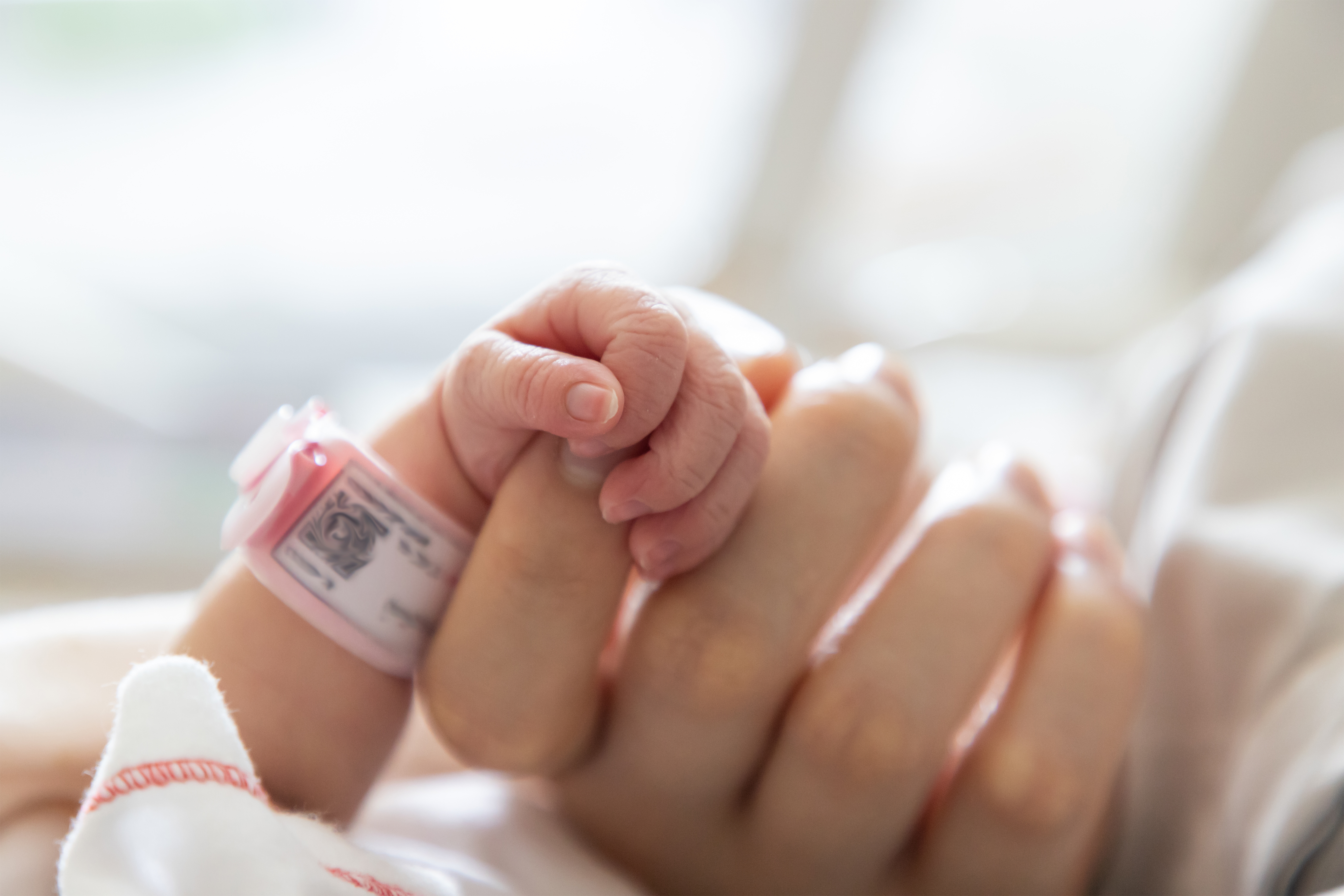 A baby's hand clutching a woman's finger | Source: Shutterstock