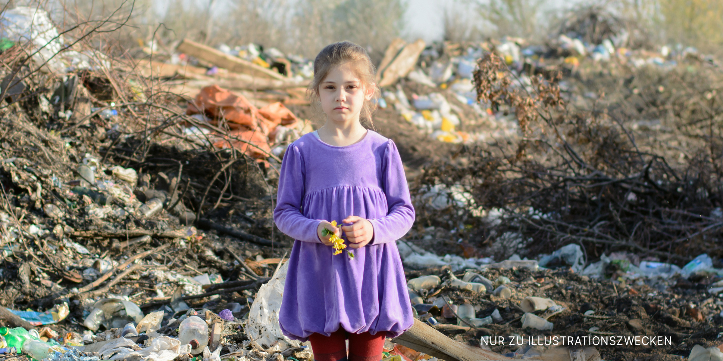 Einsames kleines Mädchen in einem violetten Kleid auf einer Mülldeponie | Quelle: Shutterstock