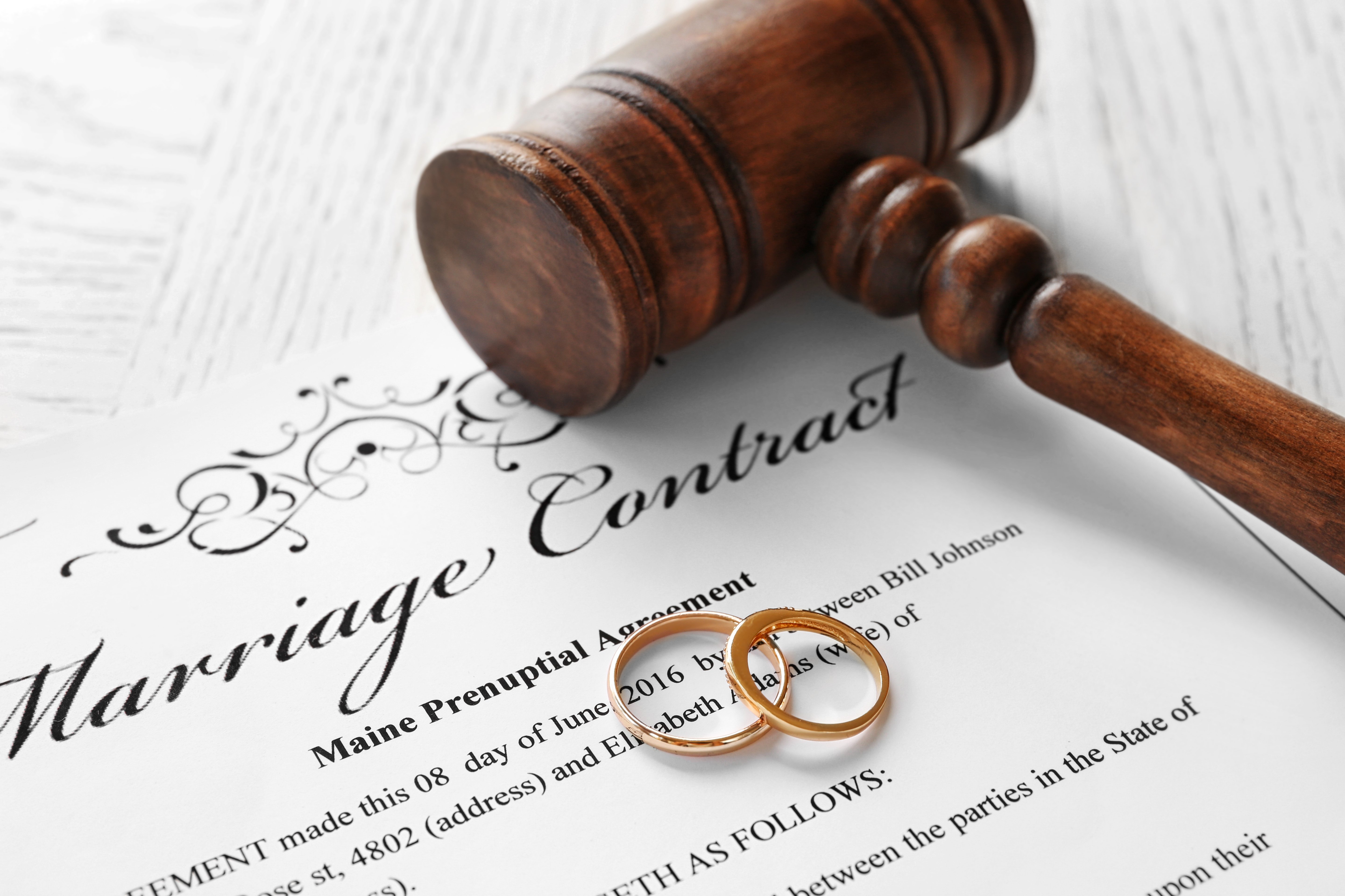 Golden wedding rings with judge gavel on marriage contract. | Photo: Shutterstock