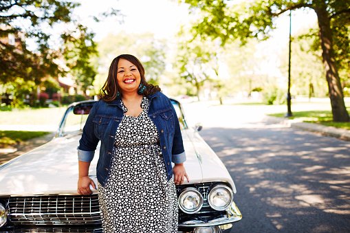 Woman leaning on hood of vintage convertible. | Photo : Getty Images