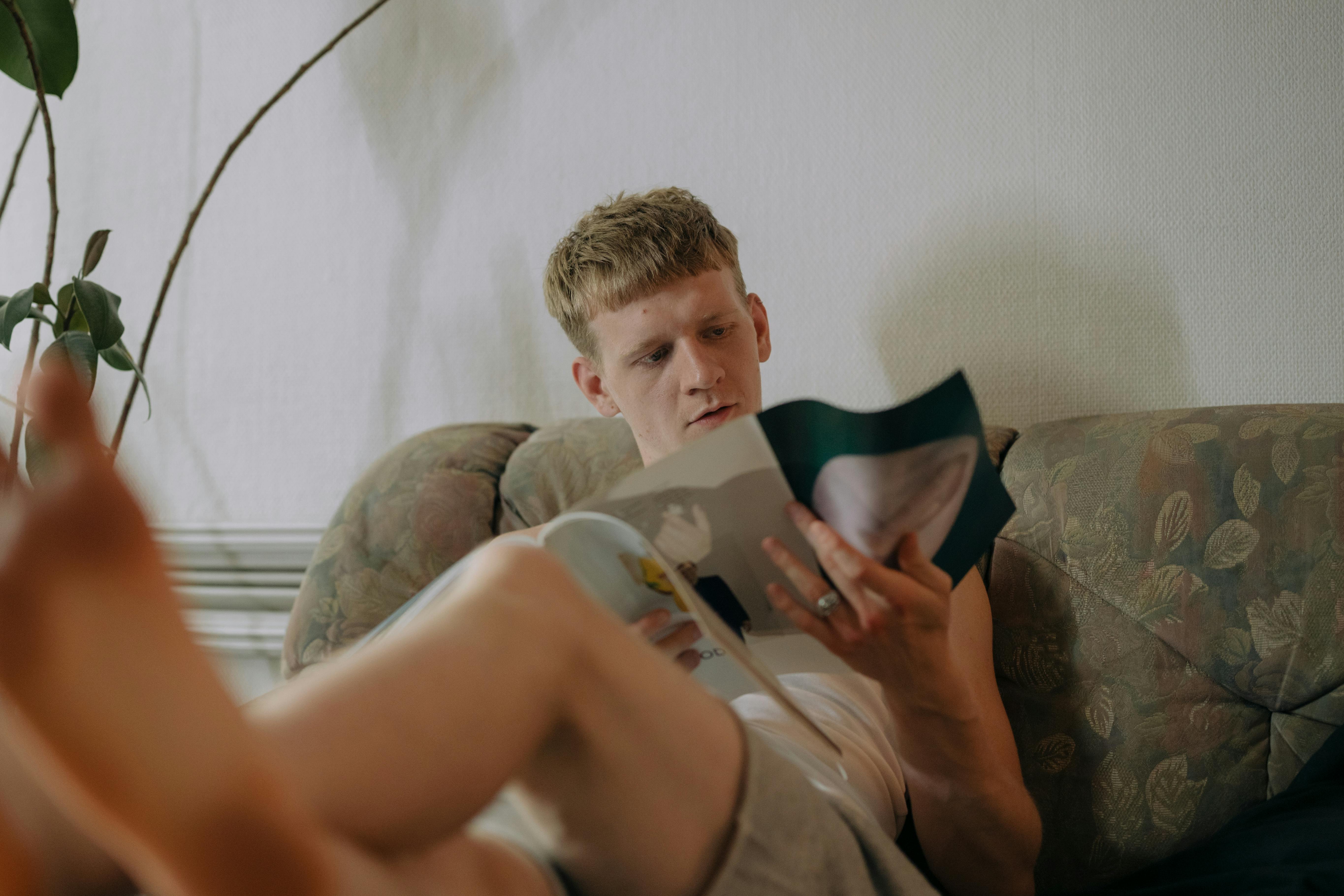 Man seated on the sofa reading a magazine | Source: Pexels