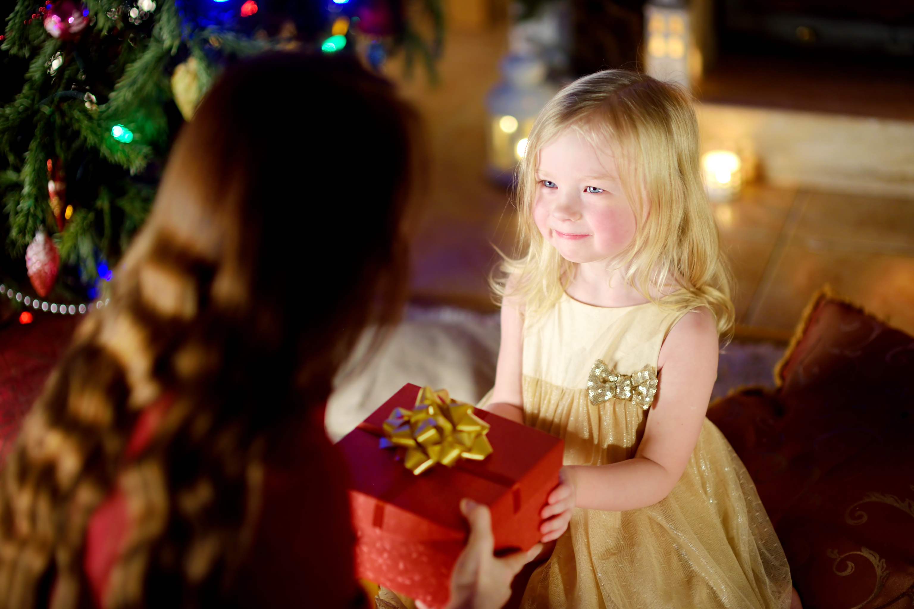 A happy little girl getting a Christmas gift from her mother | Source: Getty Images