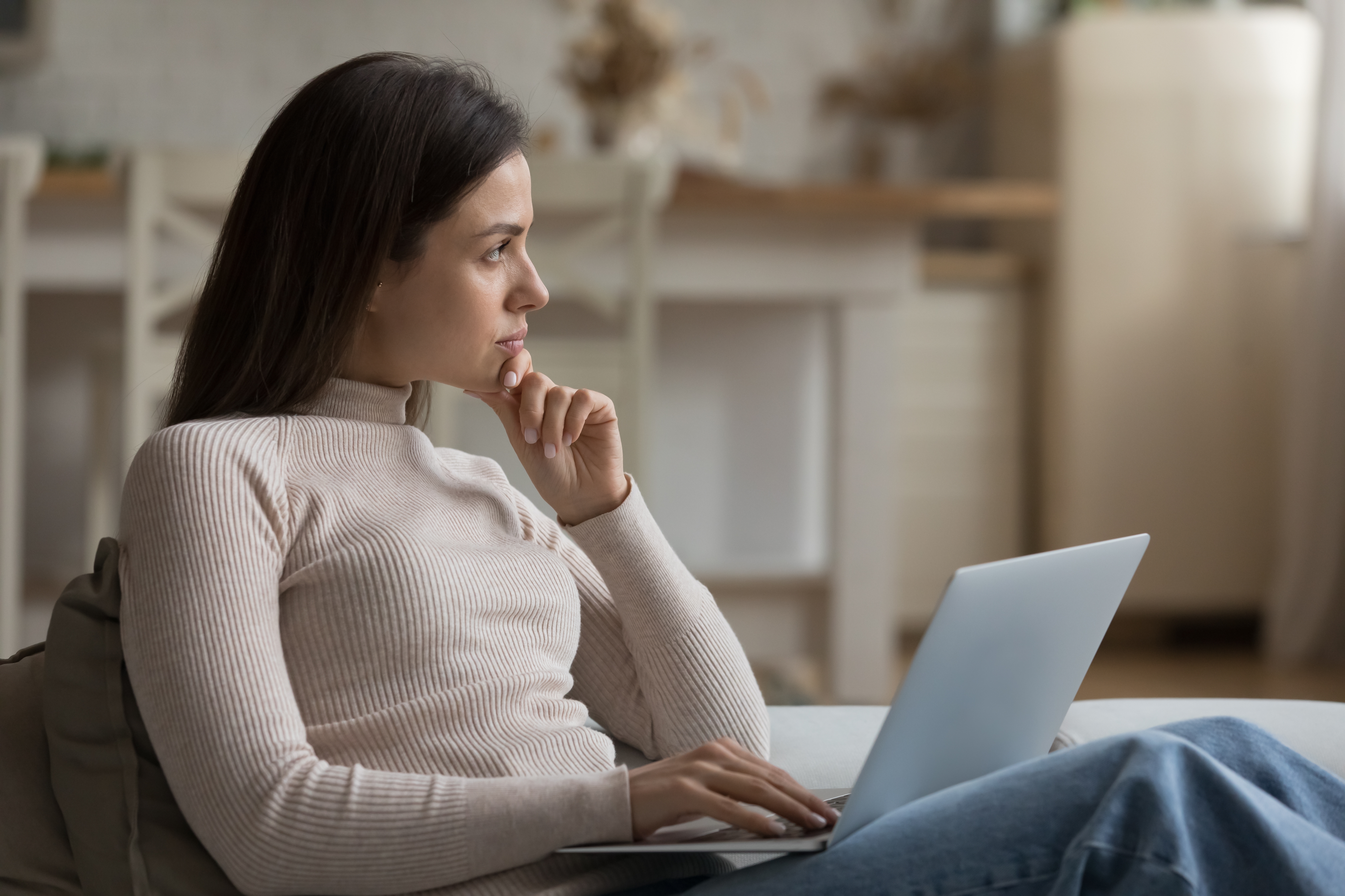 A thoughtful young woman staring into the distance while using her laptop | Source: Shutterstock