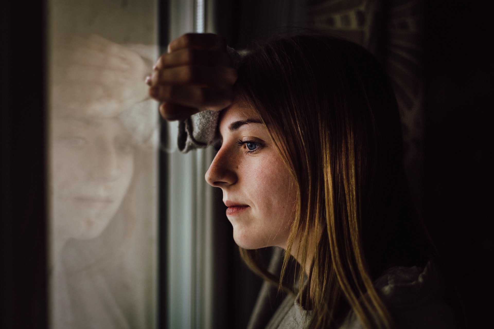 A woman looking outside a window | Source: Pexels