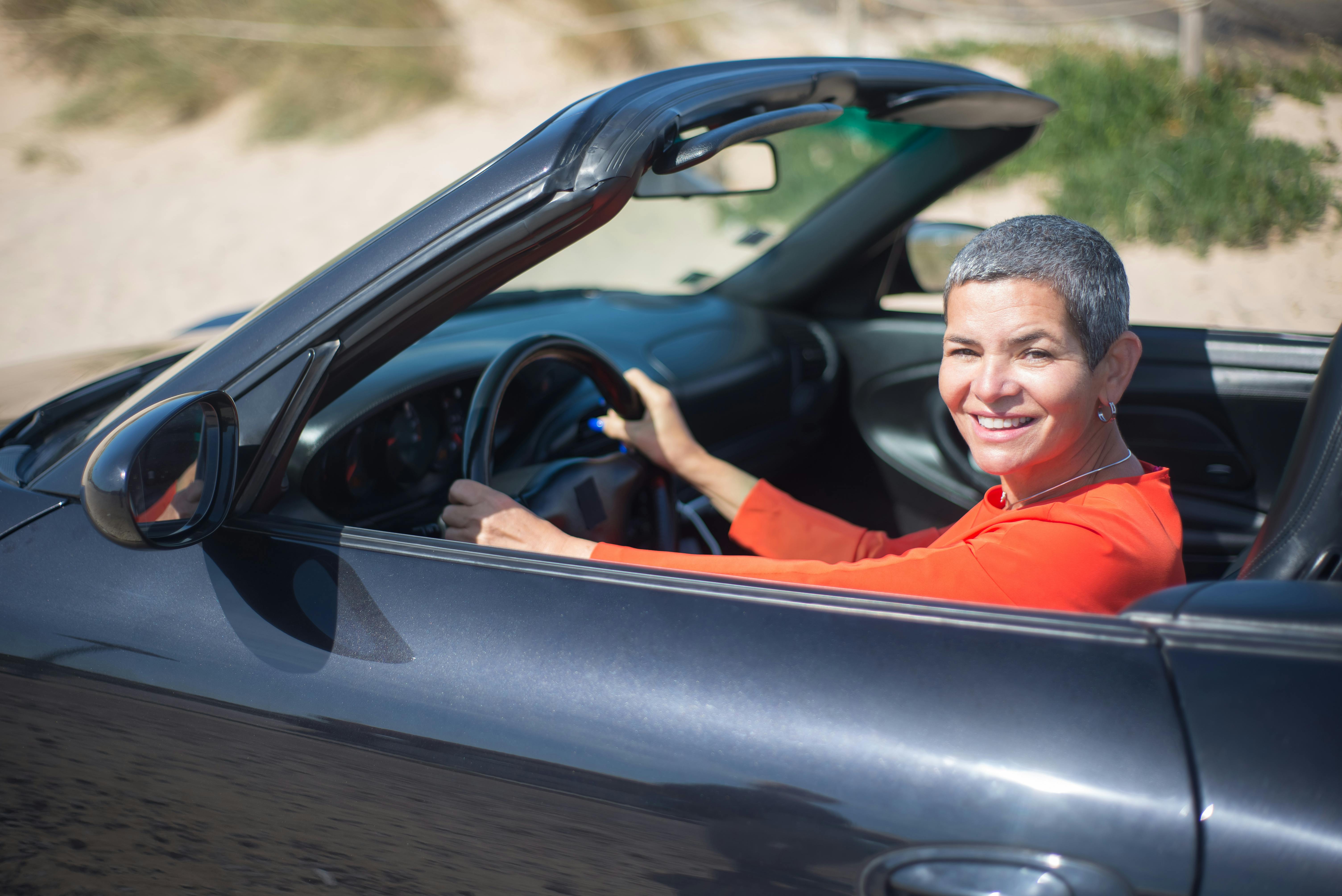 A smiling woman driving a Cabriolet | Source: Pexels