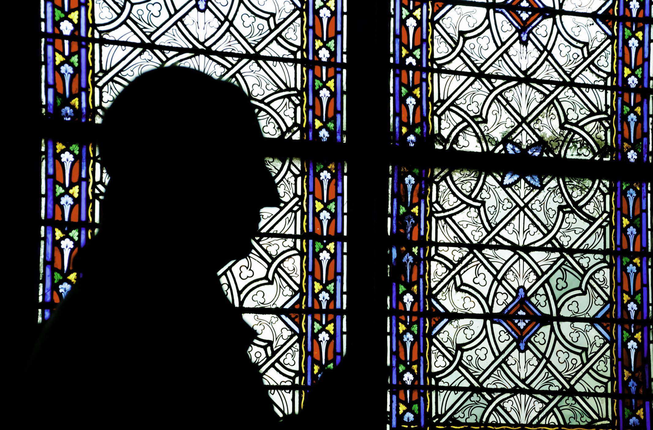 Man praying in front of stained glass window in church | Photo: Getty Images