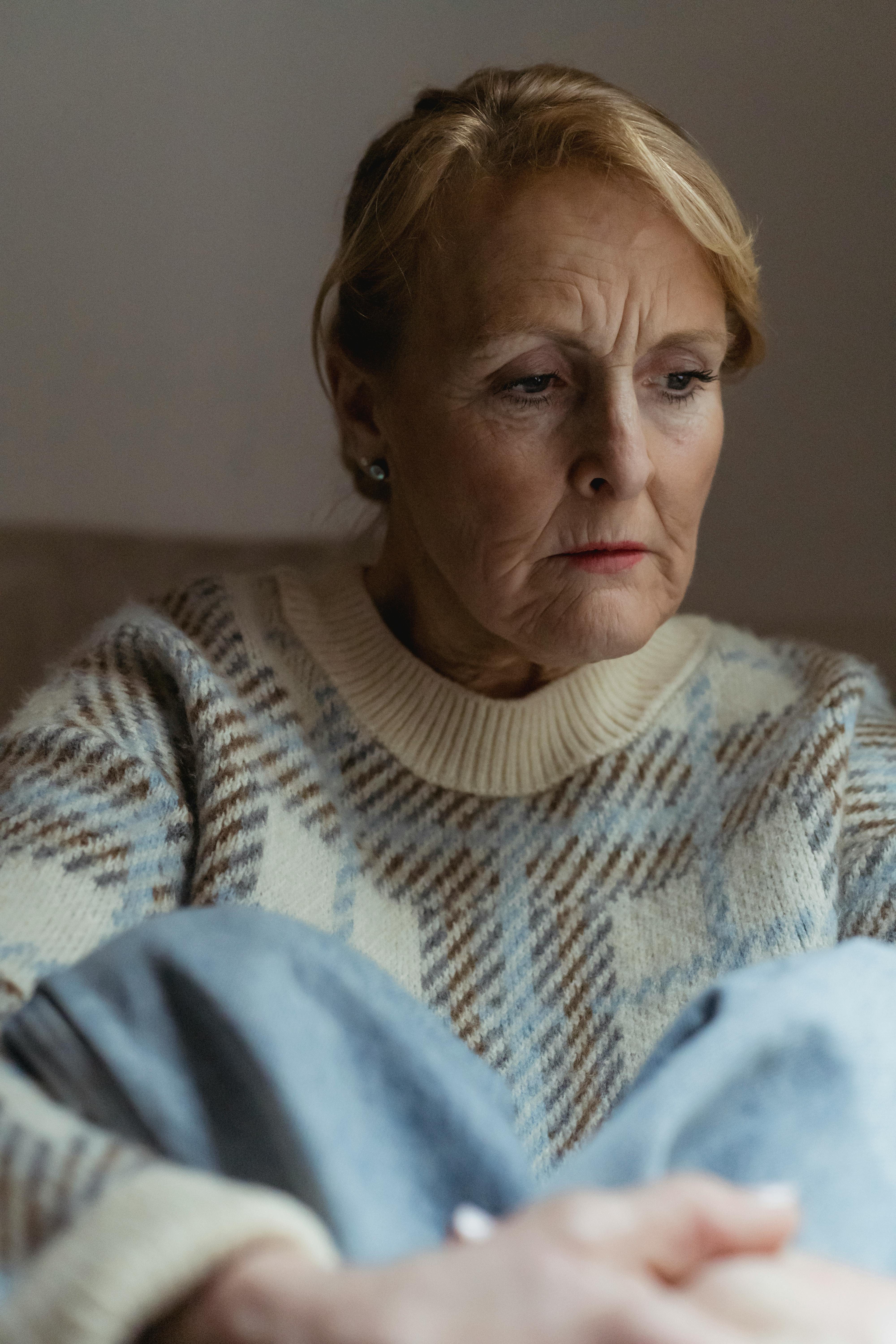 An upset older woman looking down and to the side | Source: Pexels